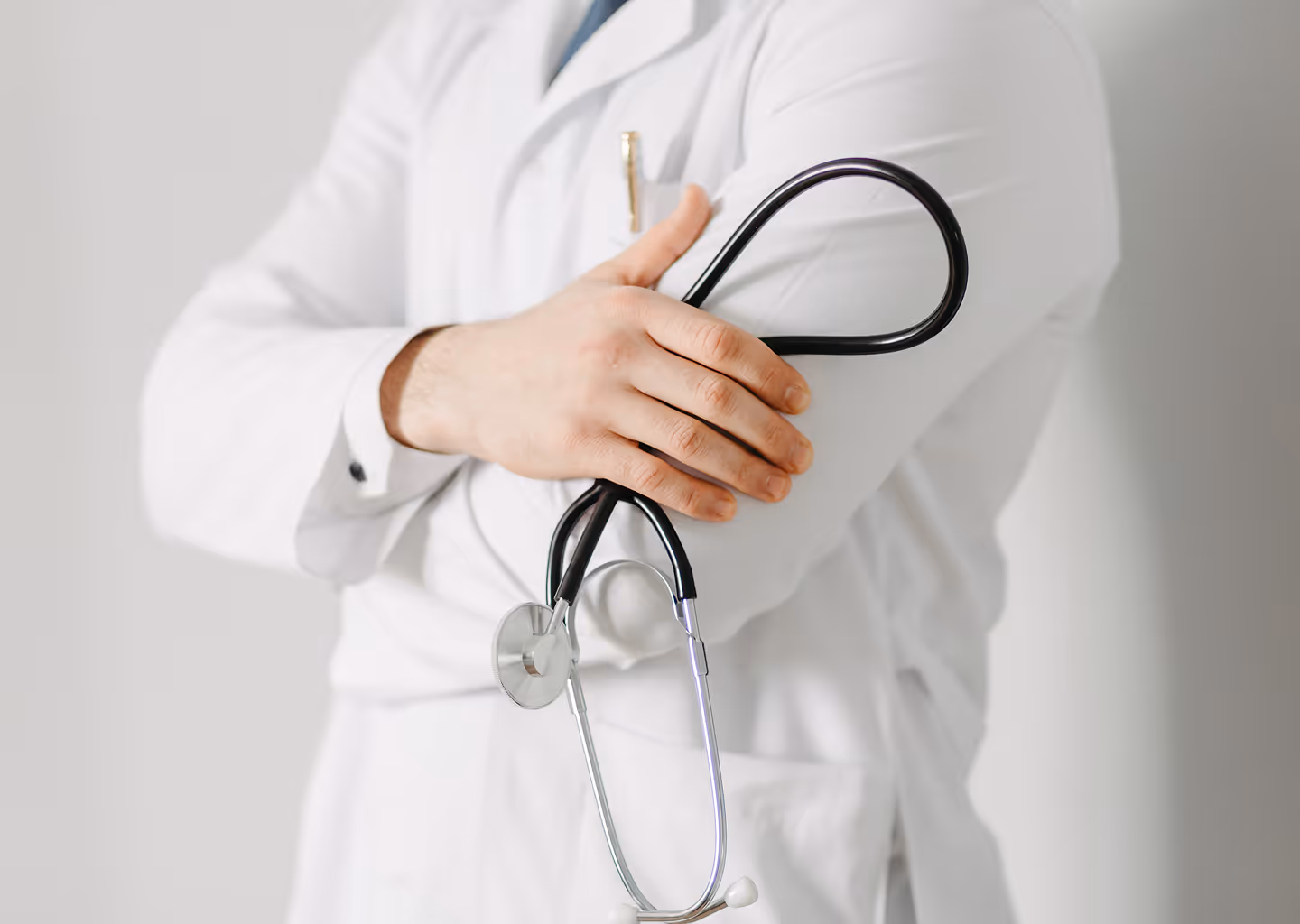 Healthcare professional in a white coat holding a stethoscope across their chest.