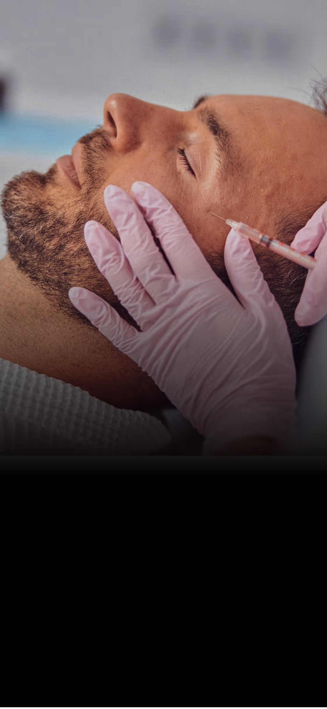 Close-up of a man with eyes closed receiving a facial injection from a gloved hand.