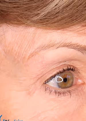 Close-up of a light brown eye with natural eyelashes and light skin showing fine wrinkles near the corner.