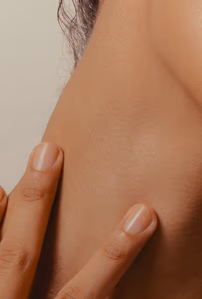 Close-up of a person’s shoulder with two fingers gently touching the skin.