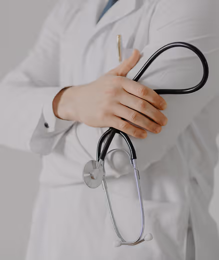 Medical professional in white coat holding a black stethoscope.