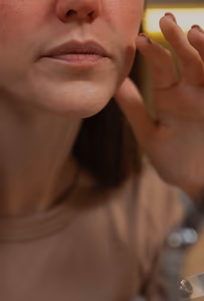 Close-up of a woman touching her face near her ear with her fingers.