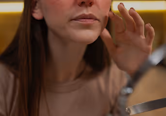 Close-up of a woman adjusting her hair while looking into a mirror.