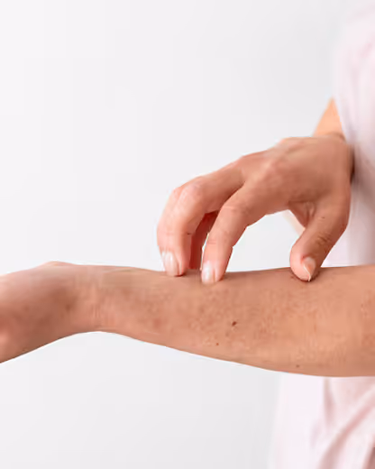 Person scratching the inner forearm against a plain white background.