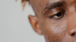 Close-up of a person's eye and part of their face with a neutral expression.