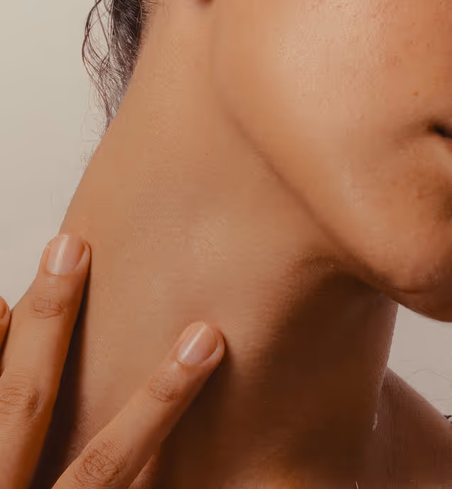 Close-up of a person touching the side of their neck and jawline with two fingers.