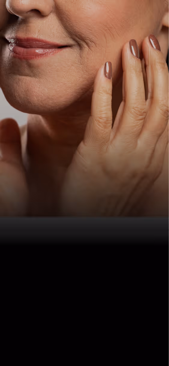 Close-up of an older woman’s face and hand showing wrinkles and manicured nails.