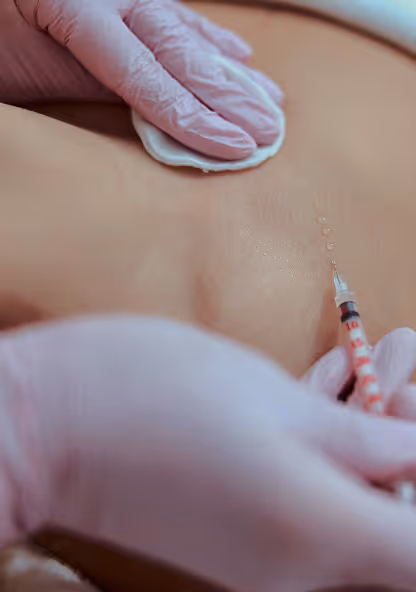 Gloved hands applying a cotton pad and injecting a skin treatment on a bare chest.