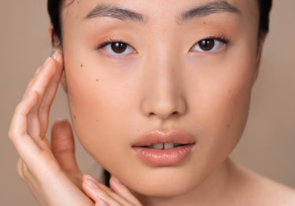 Close-up of young woman with smooth skin gently touching her face and neck.