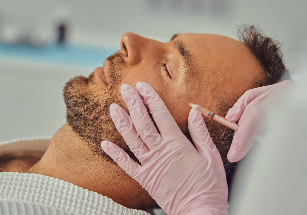 Close-up of a man receiving a facial injection from a gloved medical professional.