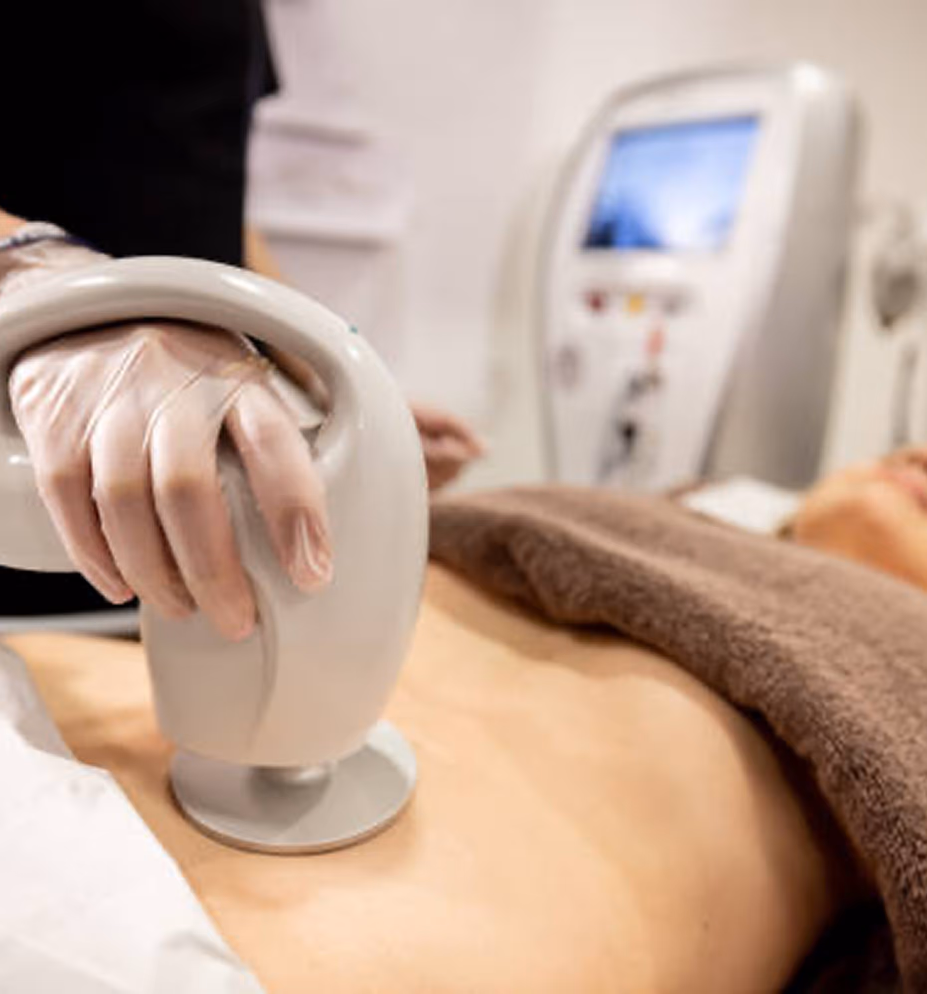Hand with glove using a medical device on a person's bare stomach during treatment.