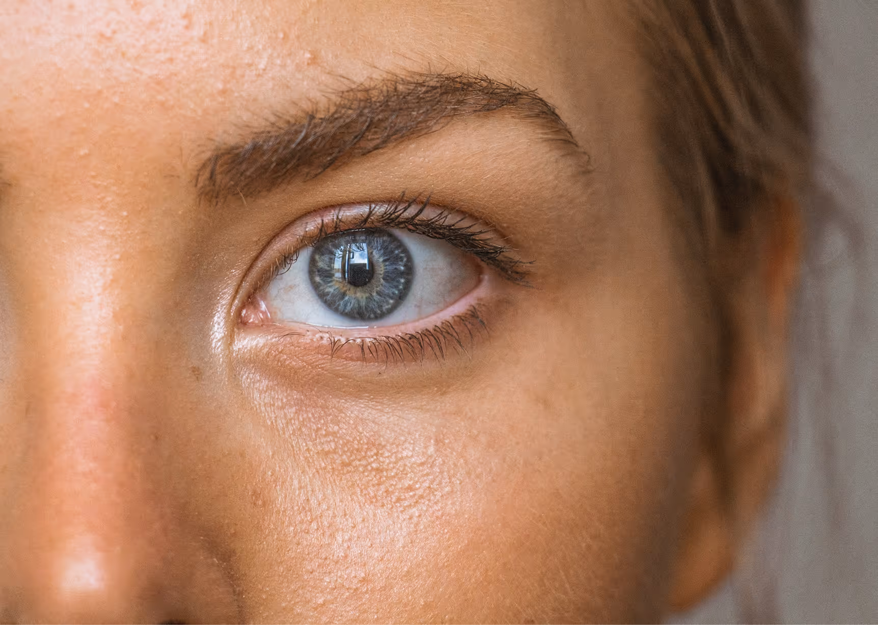 Close-up of a blue eye with natural skin texture and eyebrow visible around it.