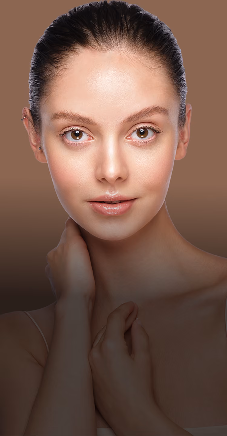 Close-up portrait of a young woman with clear skin, brown eyes, and dark hair pulled back, posing with one hand on her neck against a brown background.