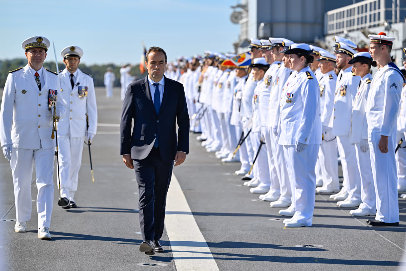 Sébastien Lecornu qui marche devant  des militaires de la marine 