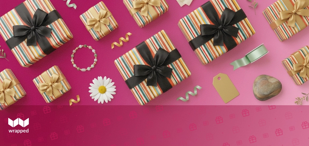 A delicate bracelet resting on a wrapped gift box beside a handwritten card and fresh flowers
