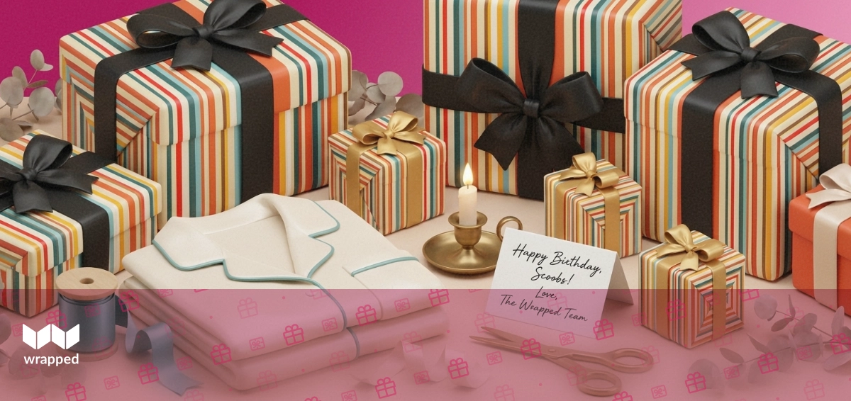 Folded silk pyjamas, satin ribbon, a birthday candle and a handwritten card arranged on a dressing table for wrapping