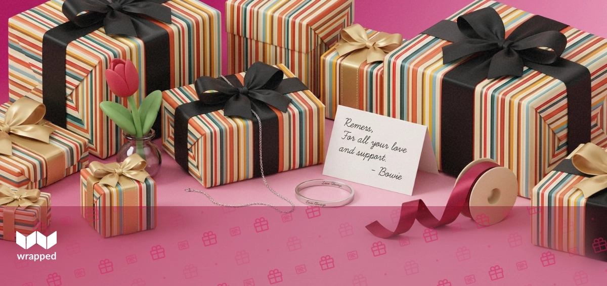 Silver necklace, engraved bracelet and a handwritten message card arranged with a red tulip and ribbon spool
