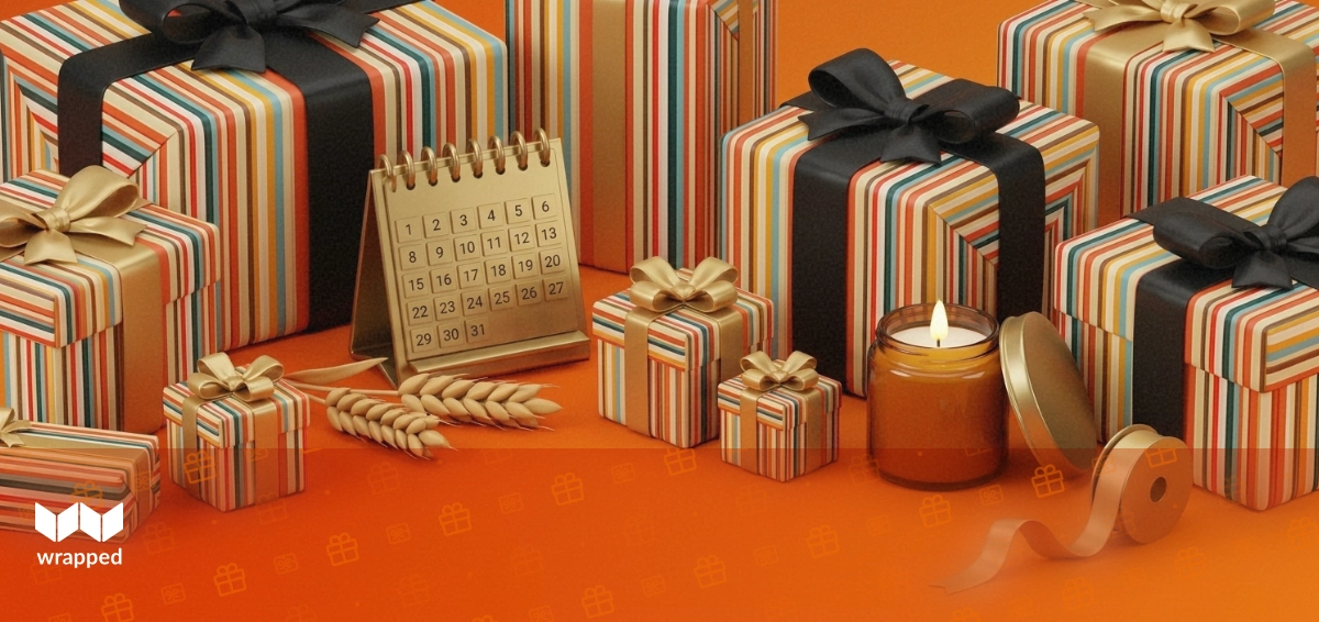Amber-lit still life with a brass desk calendar, dried wheat, a lit candle, and a spool of gold ribbon