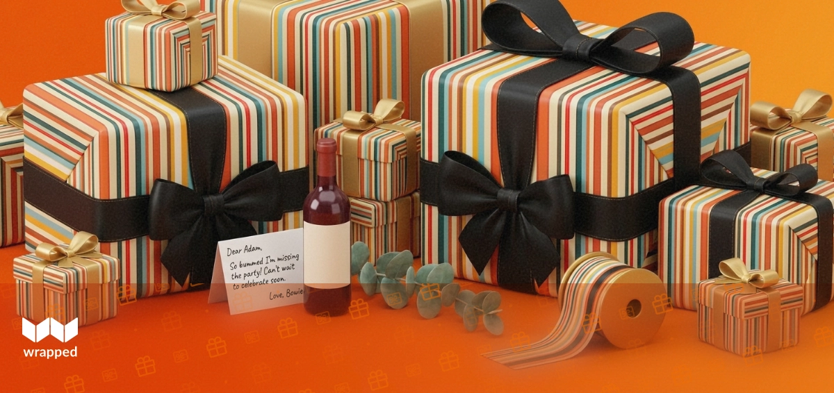 Amber-lit still life with a wine bottle, wrapped gift box, ribbon spool and handwritten card ready to send