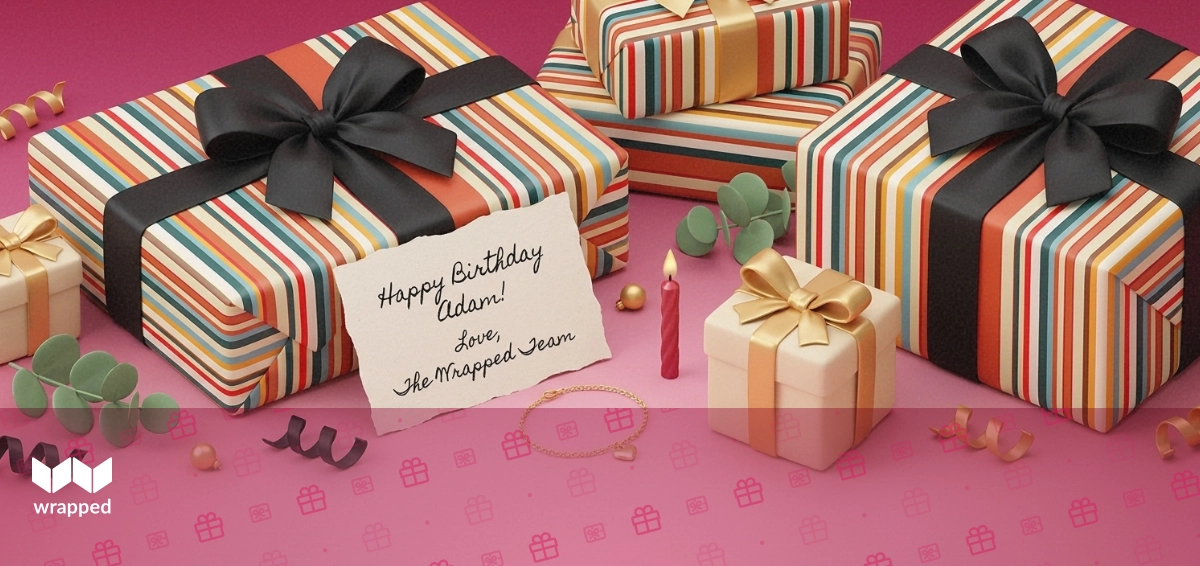 Editorial still life with a handwritten message card, gold bracelet, birthday candle and ribbon-tied gift box in rose tones