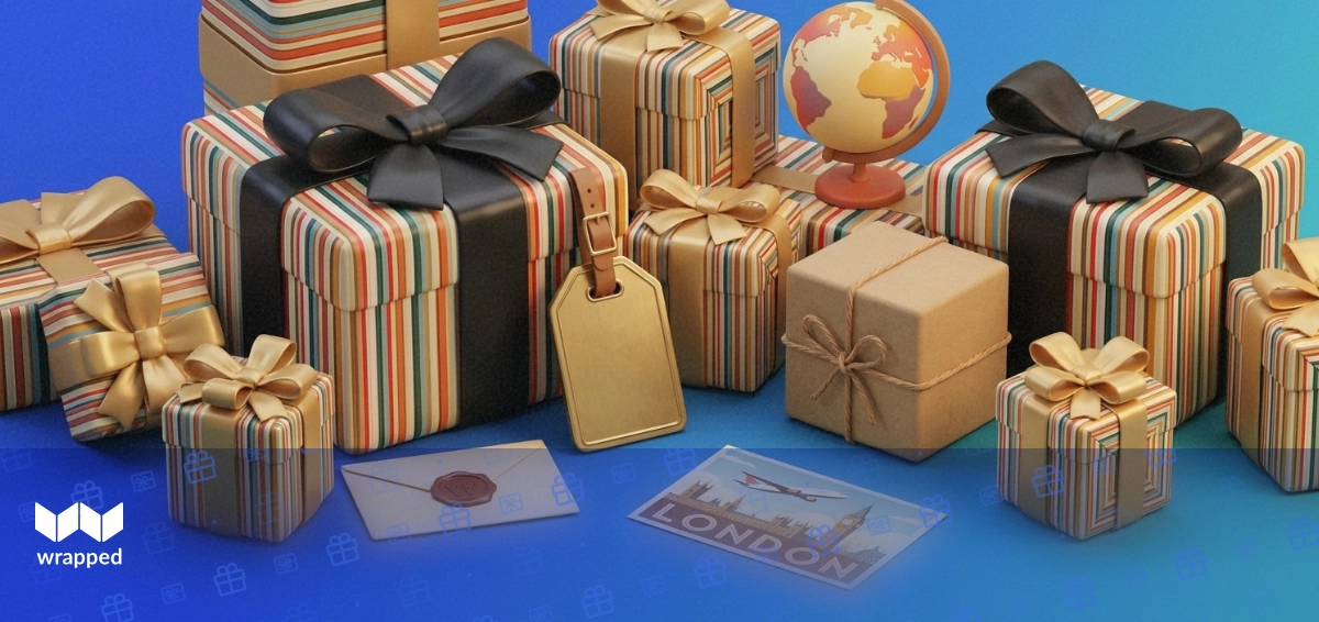 Kraft gift box with twine beside a scenic travel postcard, small globe and brass luggage tag on a warm editorial table