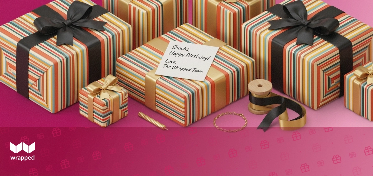Editorial still life with a handwritten card, birthday candle, gold bracelet and ribbon spool on a soft rose surface