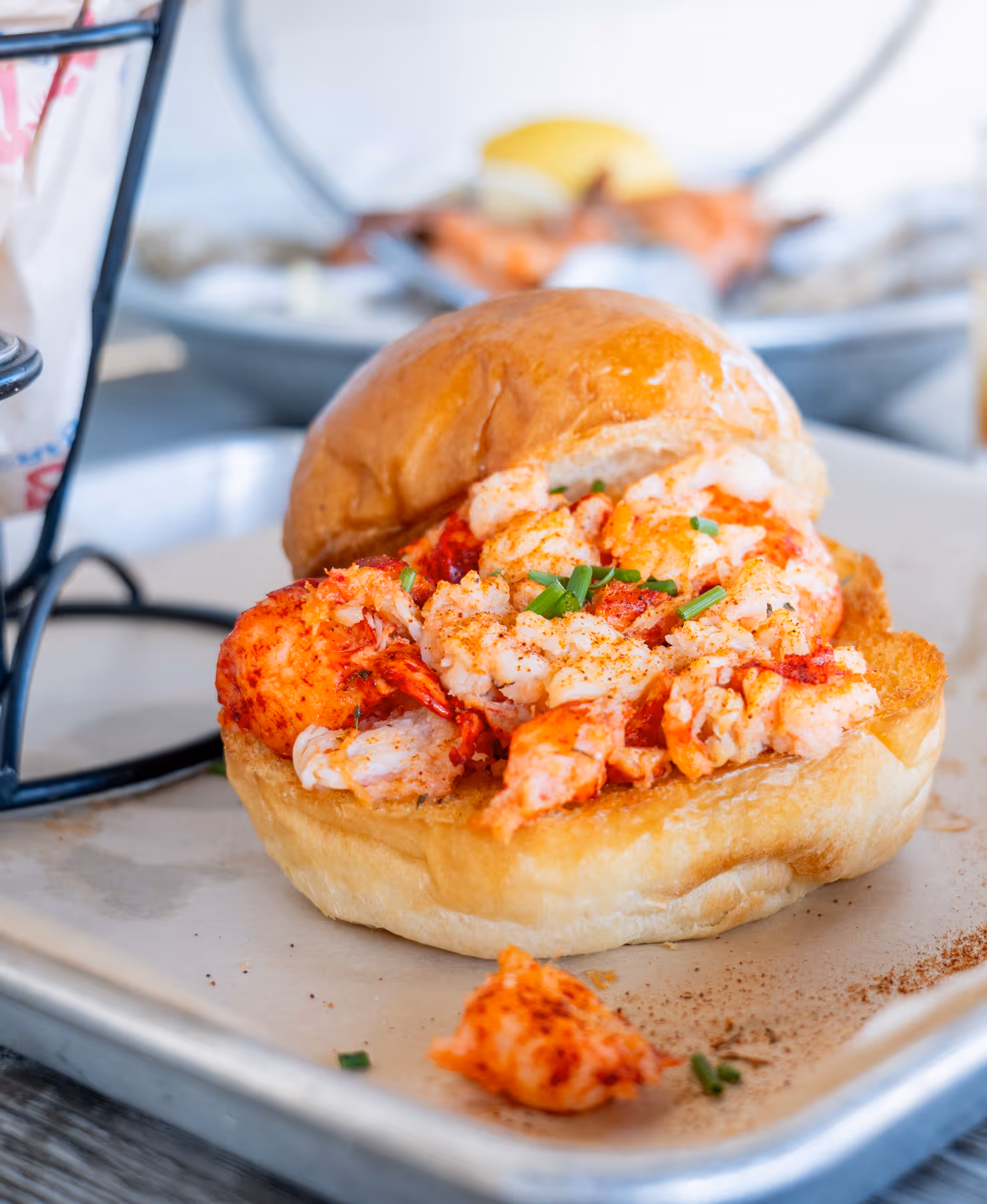 Close-up of a lobster roll sandwich with chunks of lobster meat garnished with chopped chives on a toasted bun.