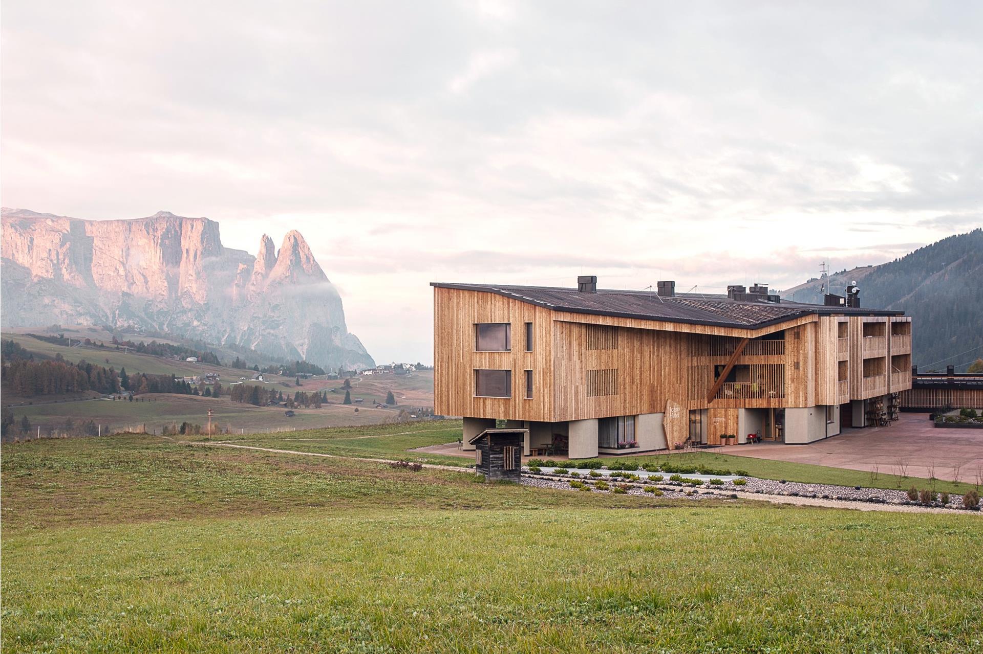 Hotel Icaro on the Alpe di Siusi, larch-clad facade and timber colonnade below the Sciliar