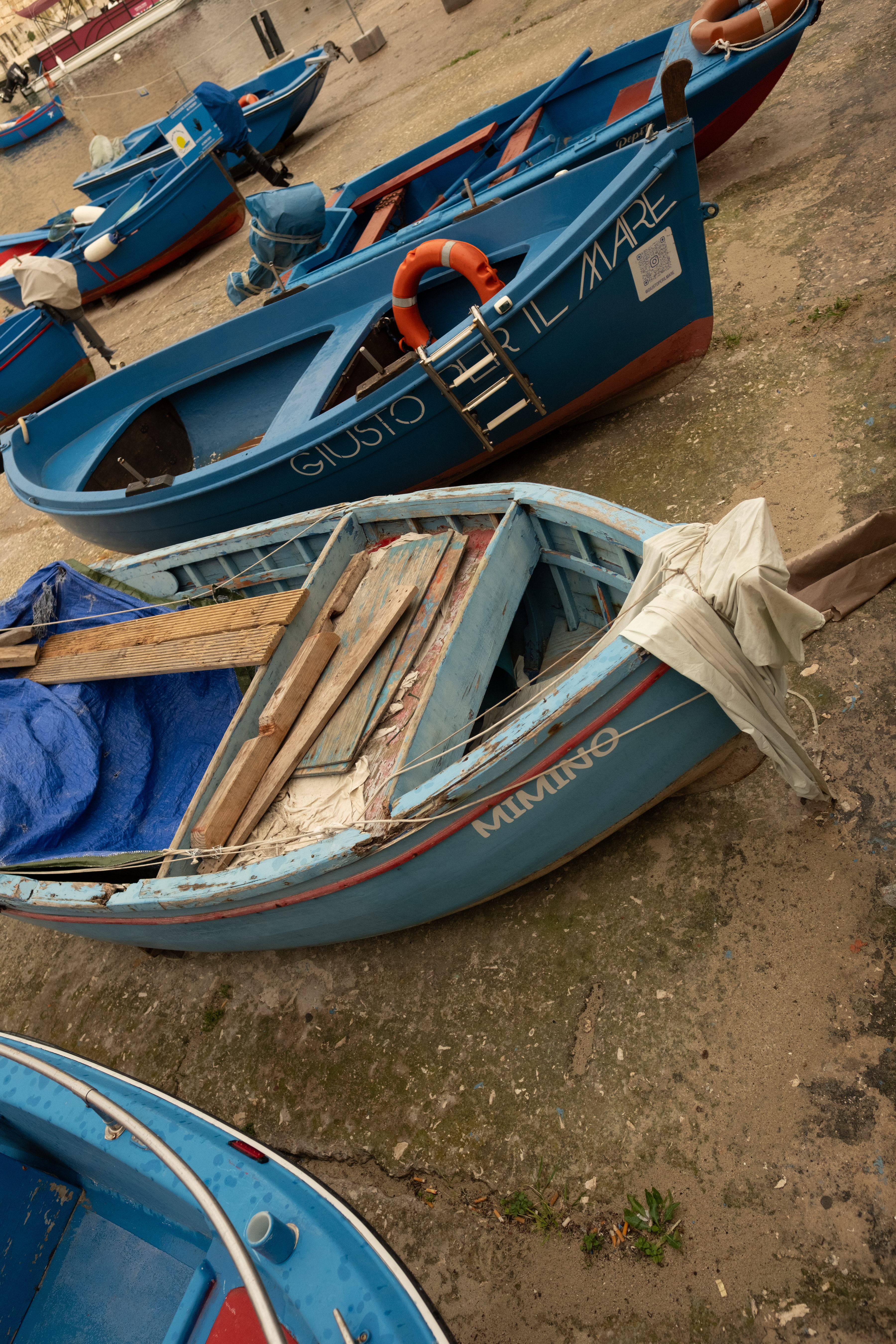 Blue wooden fishing boats pulled up on the harbour slipway