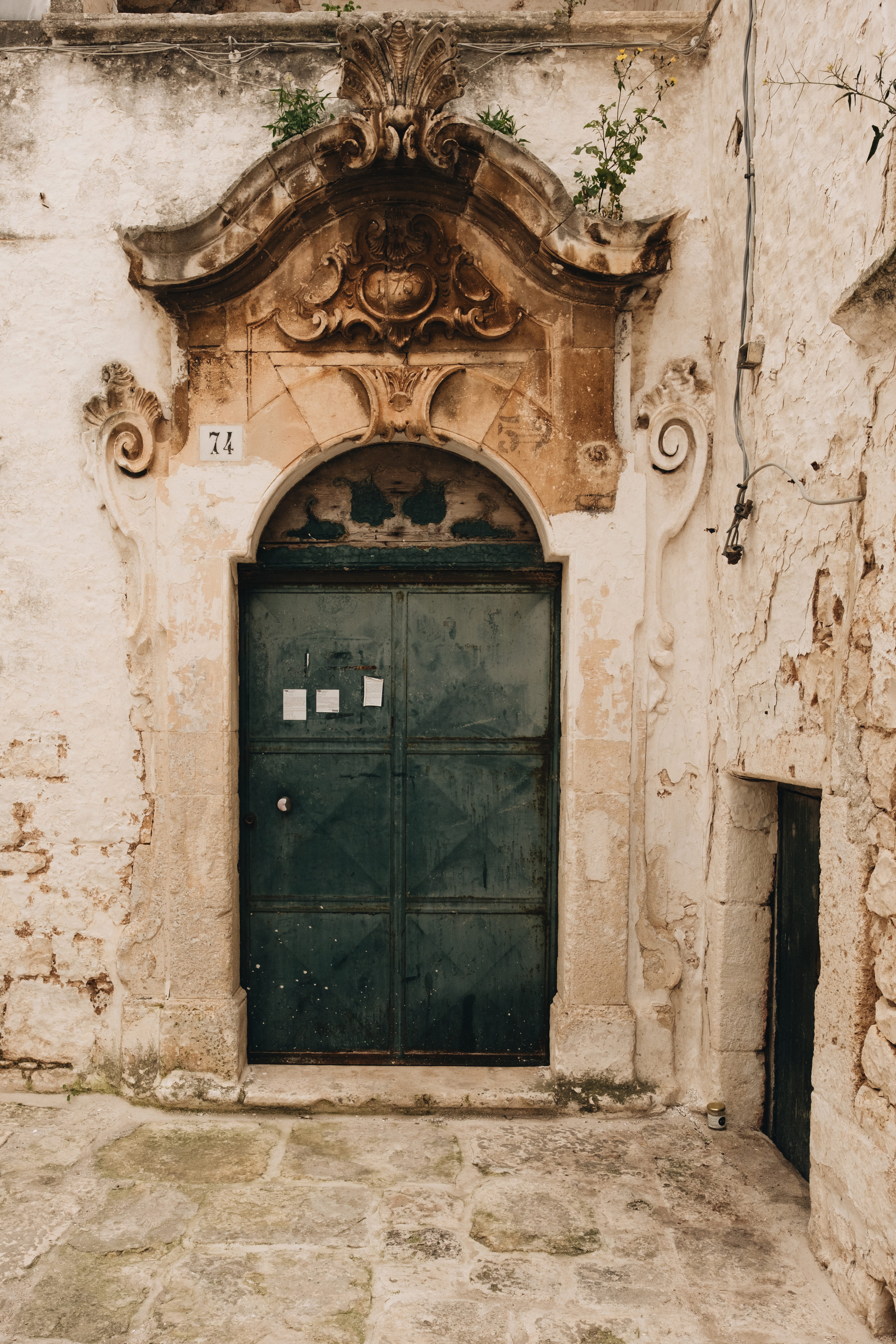Weathered green doorway No. 74 under a carved Baroque pediment