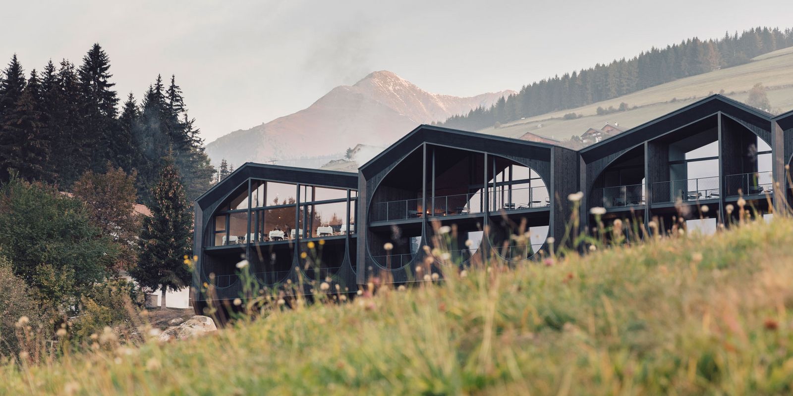 Milla Montis above Maranza in summer, blackened larch volumes with arched cut-outs
