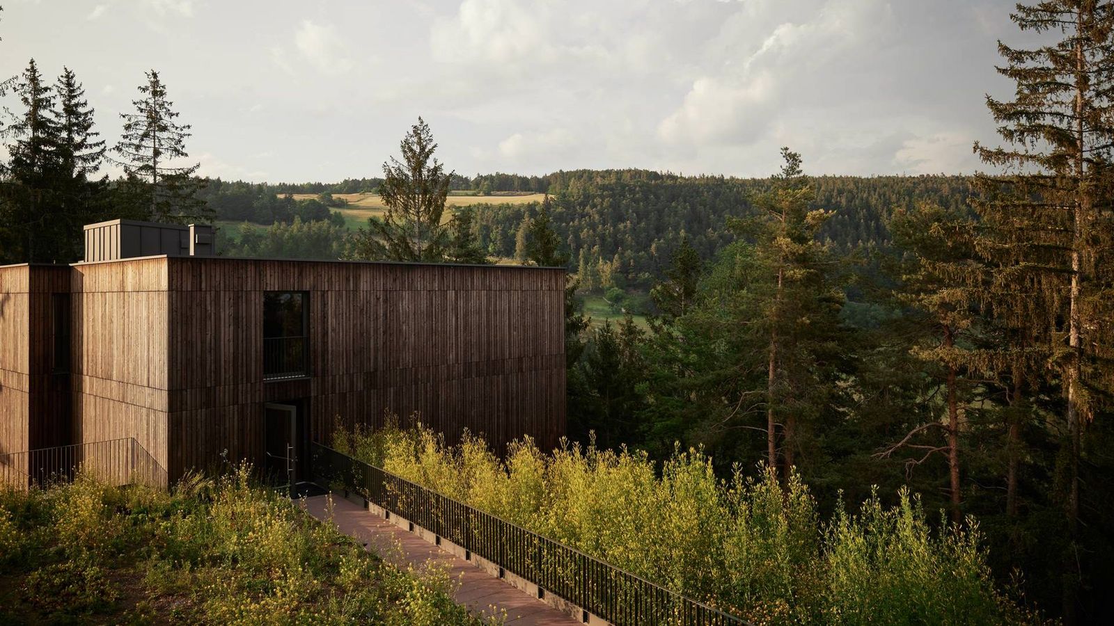 The larch facade of Hotel Saltus above Jenesien, the Dolomites across the valley