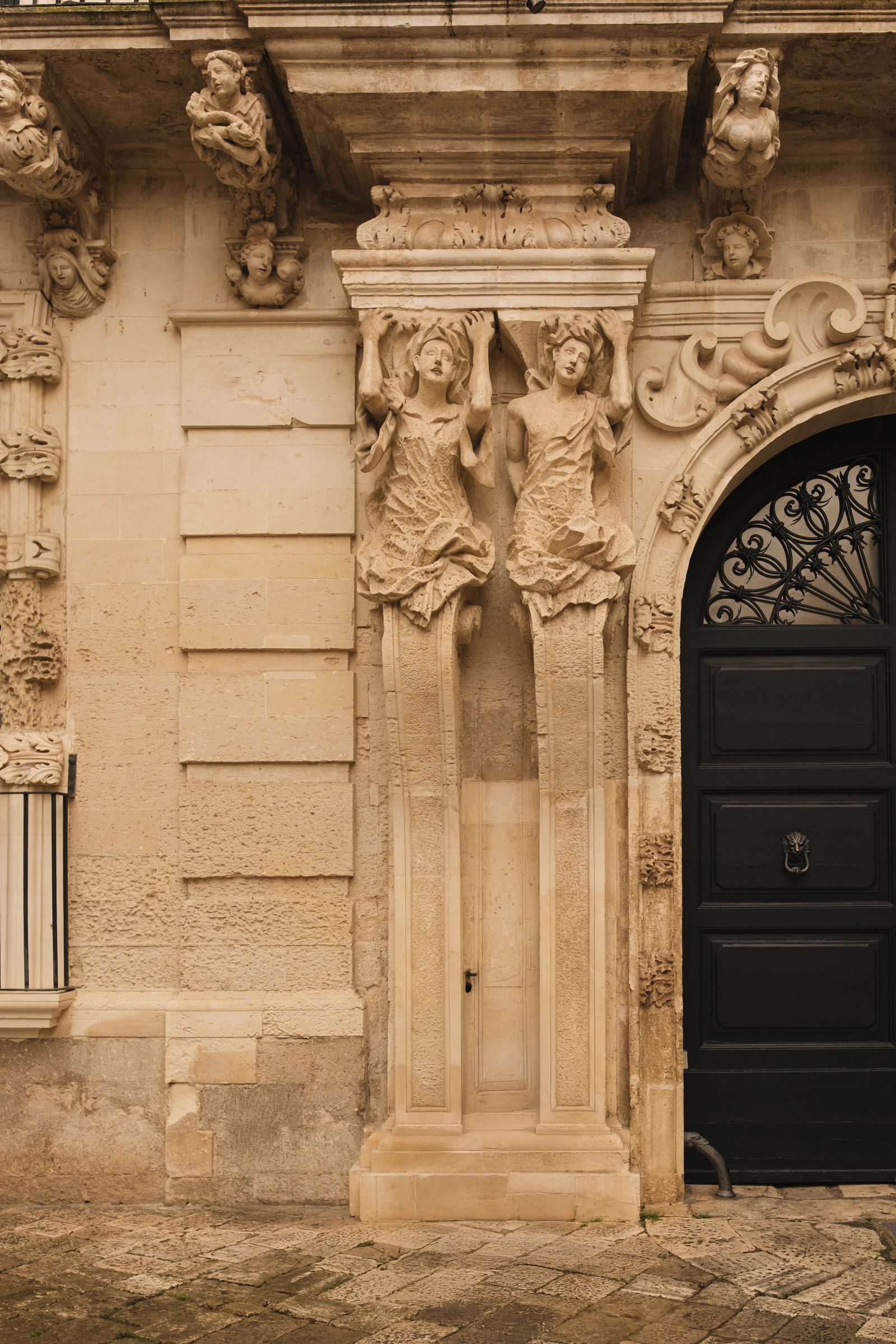 Carved caryatids beside a palazzo doorway in Lecce