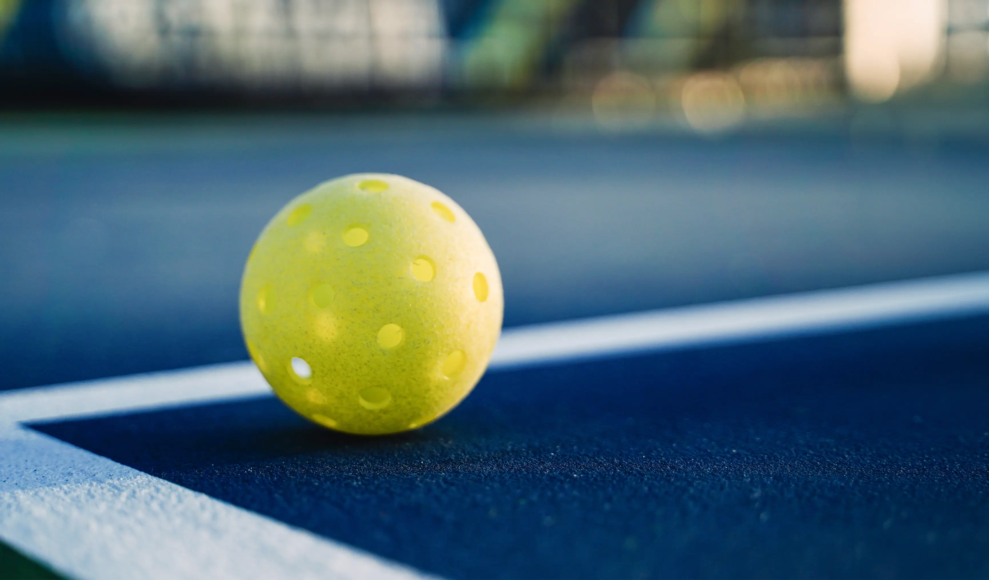 A neon yellow pickleball sitting on the Atlantic City Aces pro pickleball court