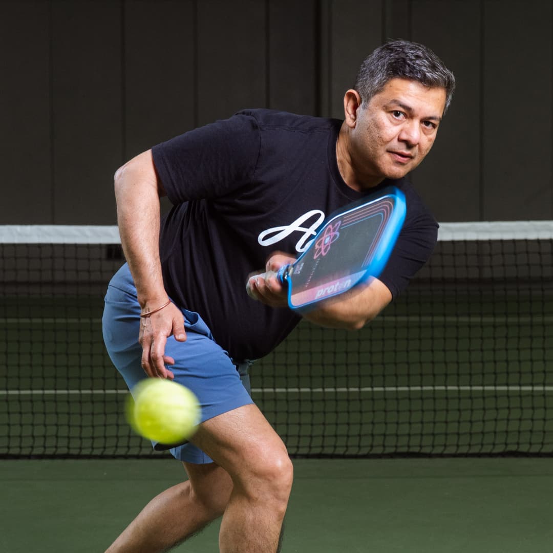Profile picture of Vinay Bahuguna wearing a black Atlantic City Aces t-shirt in a pose after hitting a yellow pickleball.