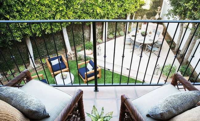 Balcony view featuring lounge chairs overlooking a green garden with a seating area.