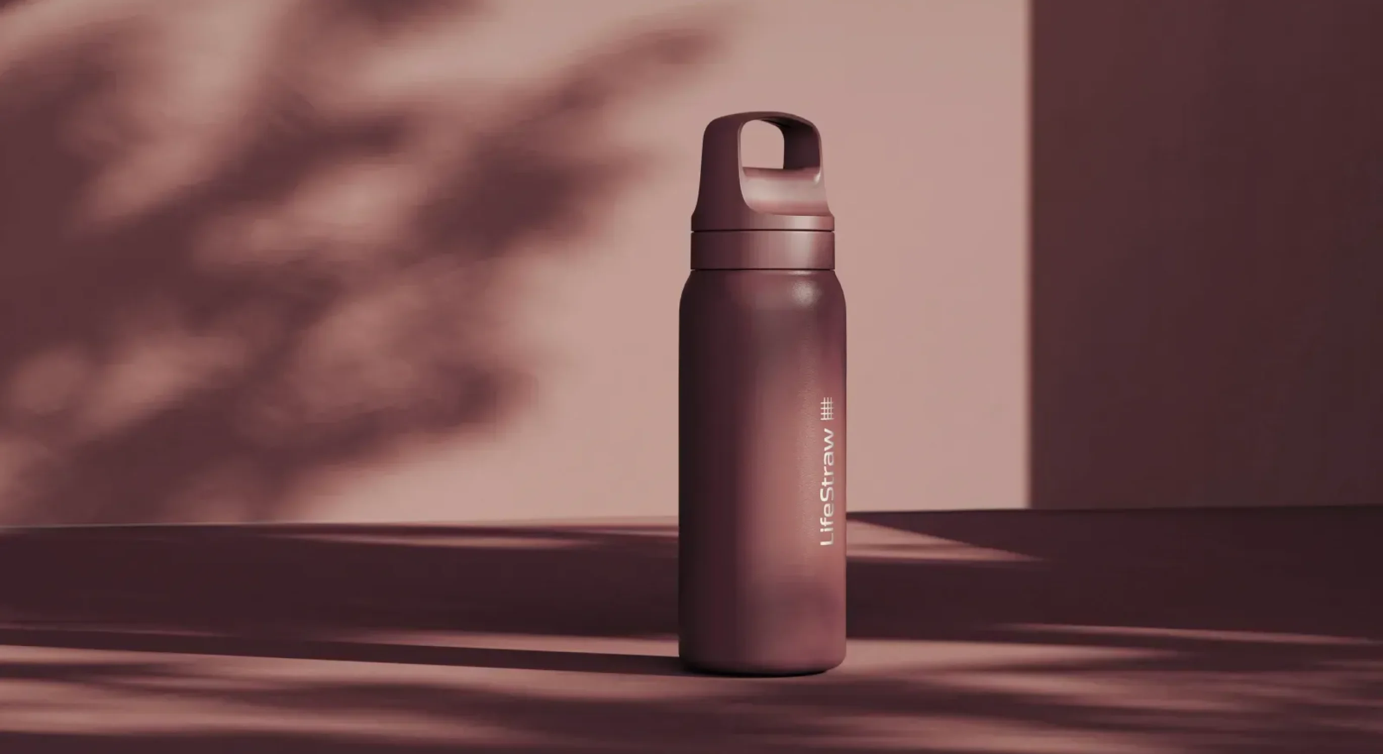 Matte brown LifeStraw water bottle standing on a matching brown surface with shadow patterns in the background.