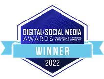 Digital+Social Media Awards 2022 winner badge with a blue hexagon shape and a ribbon banner across the middle.