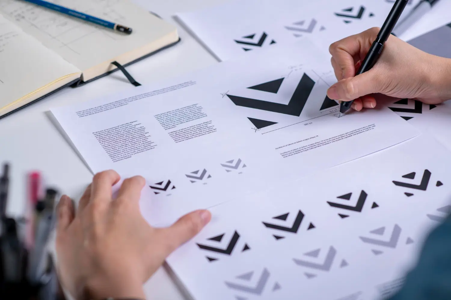 Hands sketching a logo design on paper