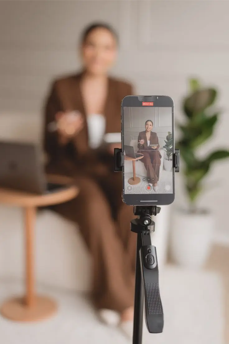 Woman being recorded on a smartphone mounted on a tripod