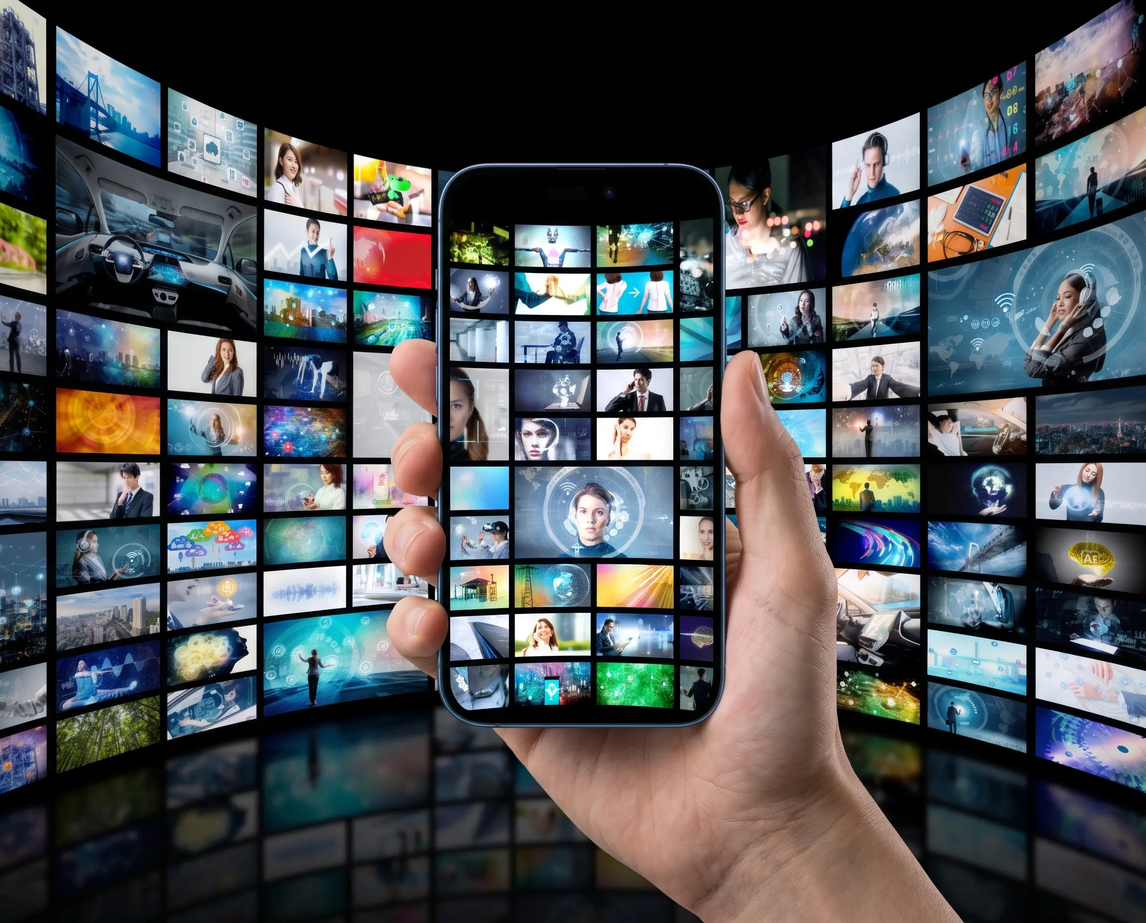 Hand holding a smartphone in front of a wall of video and media thumbnails