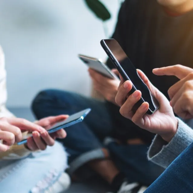 Group of people sitting together, each looking at and using their own smartphone