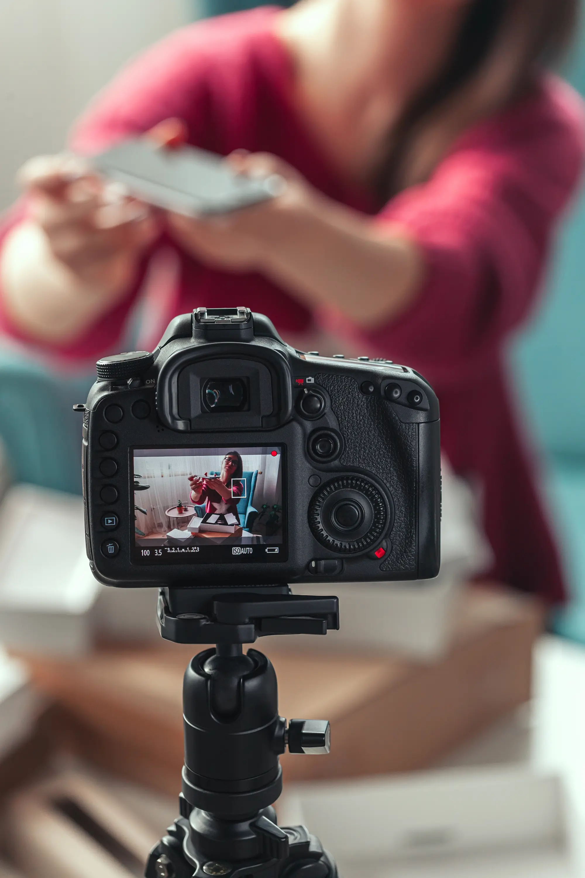 Close-up of a person's hands operating a camera mounted on a tripod.