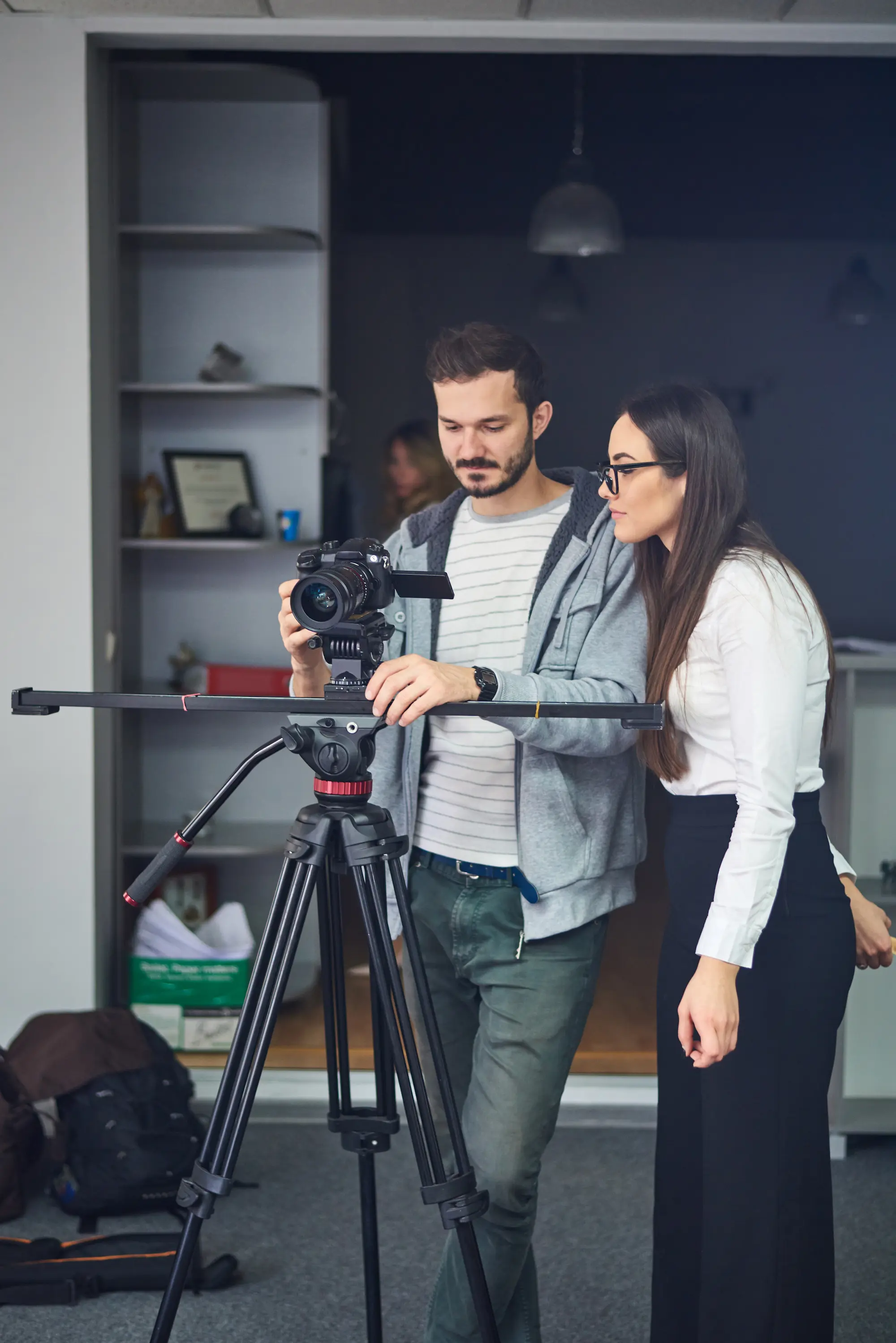 Two team members setting up a video camera on a tripod during a production shoot.