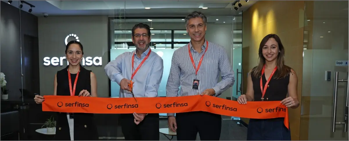 Cuatro personas sonrientes cortan una cinta naranja con logo de Serfinsa en un evento de inauguración.