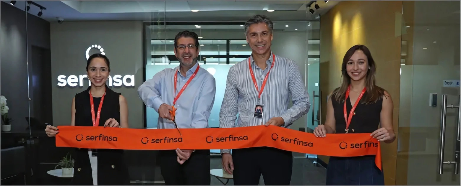 Cuatro personas sonrientes cortan una cinta naranja con logo de Serfinsa en un evento de inauguración.