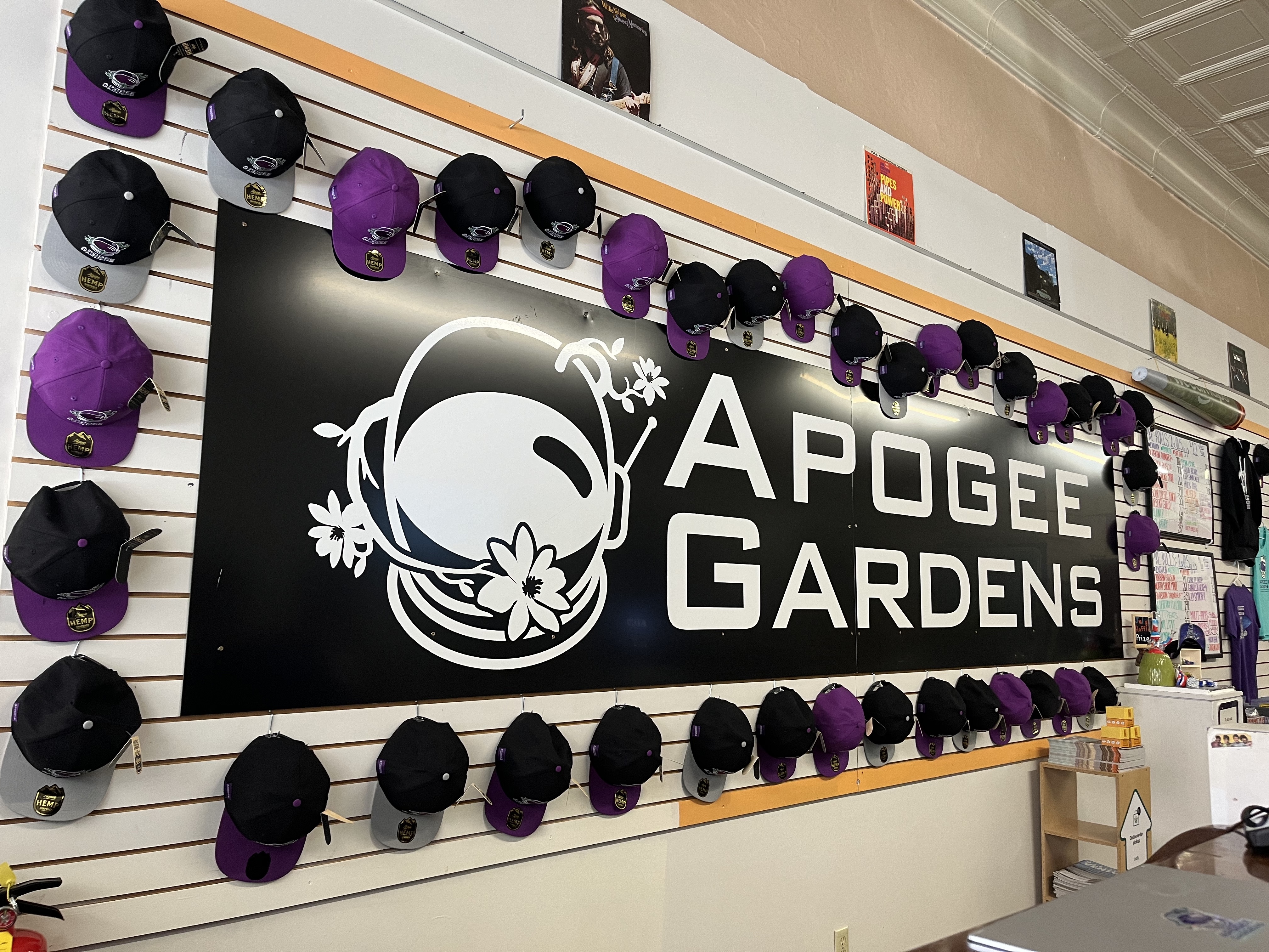 Big Apogee Gardens sign with black and purple hats displayed around the sign.