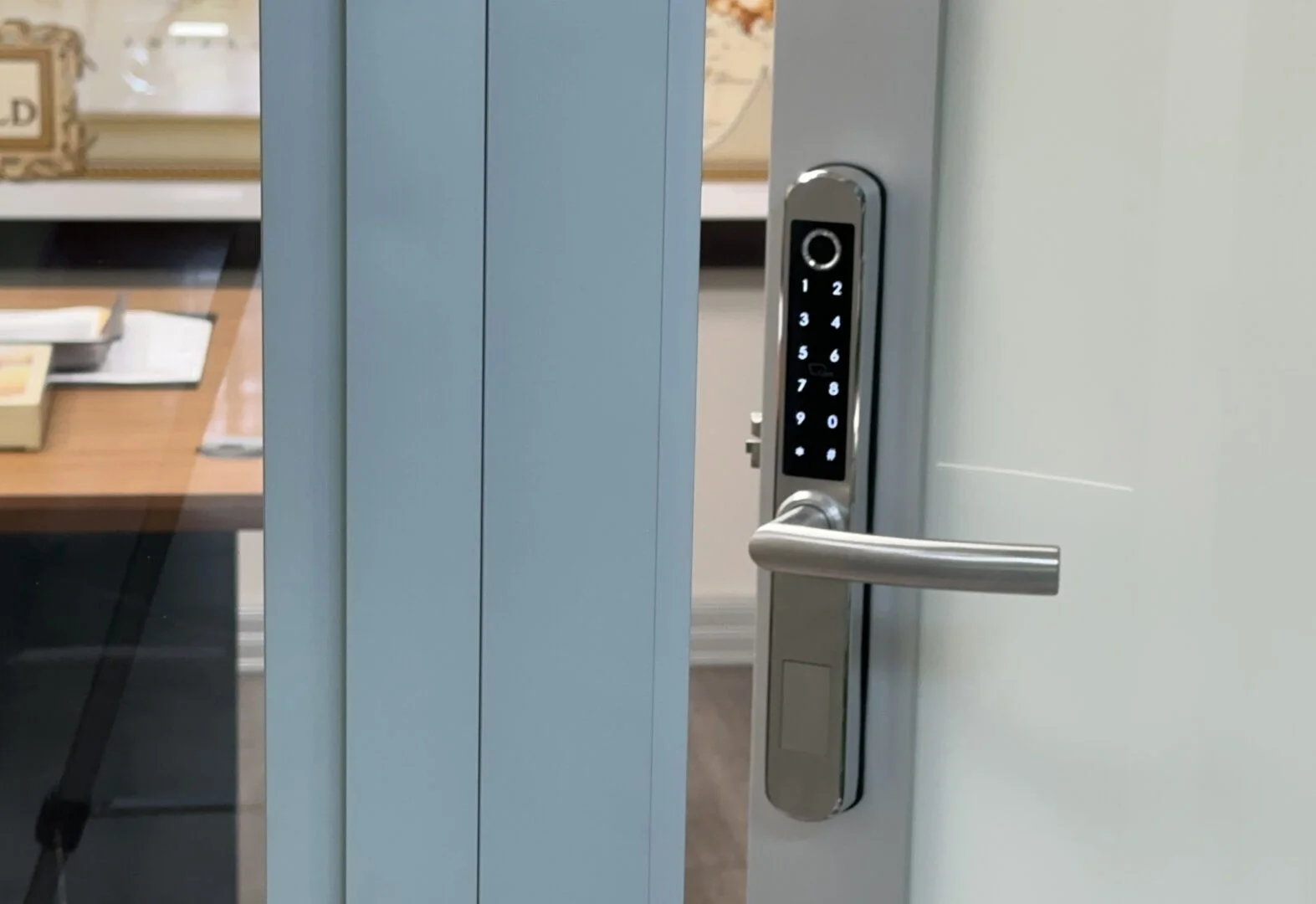 Modern silver office door with a smart keyless keypad lock showing a lit numeric keypad and a horizontal handle.