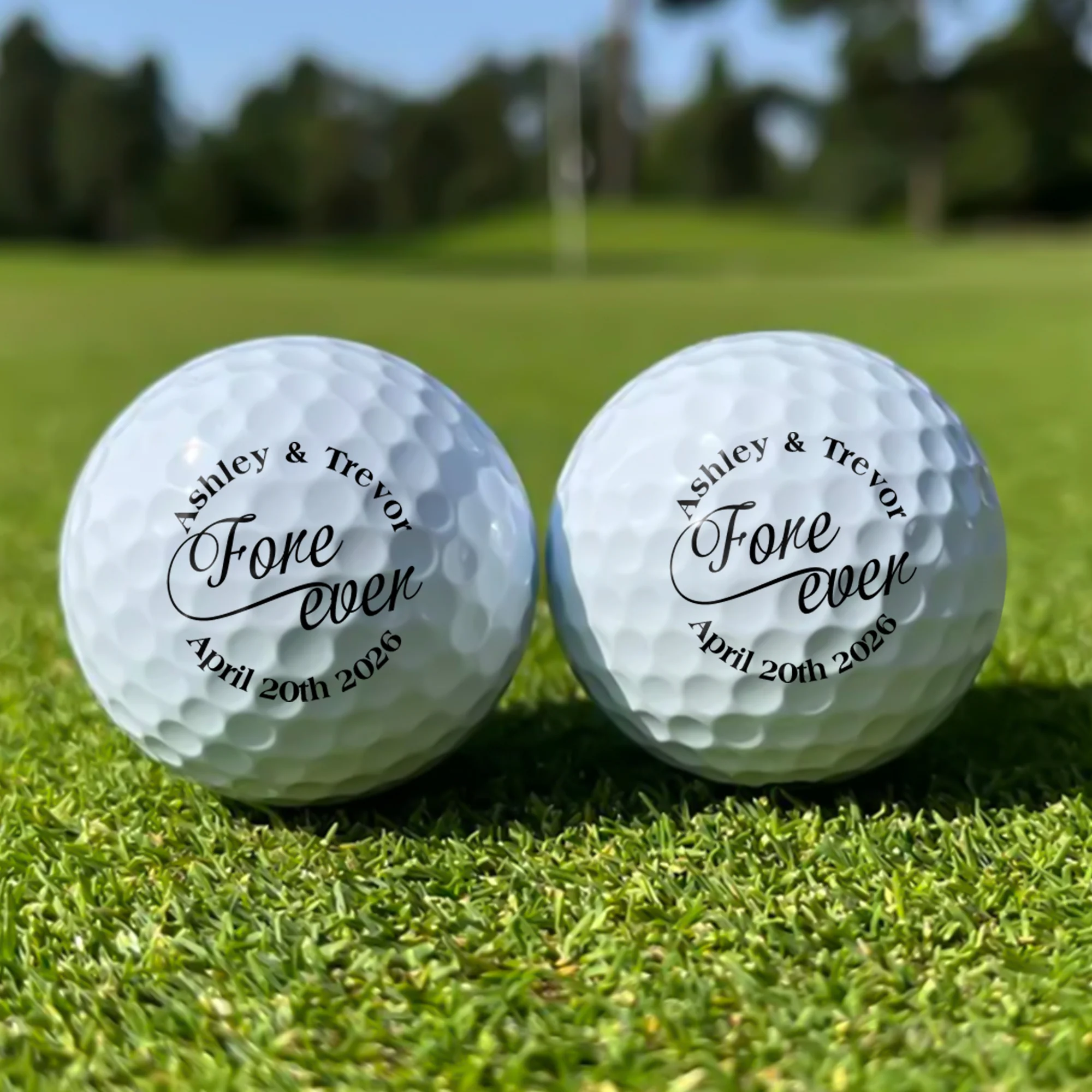 Two golf balls on grass with text: Ashley & Trevor Fore ever April 20th 2026.