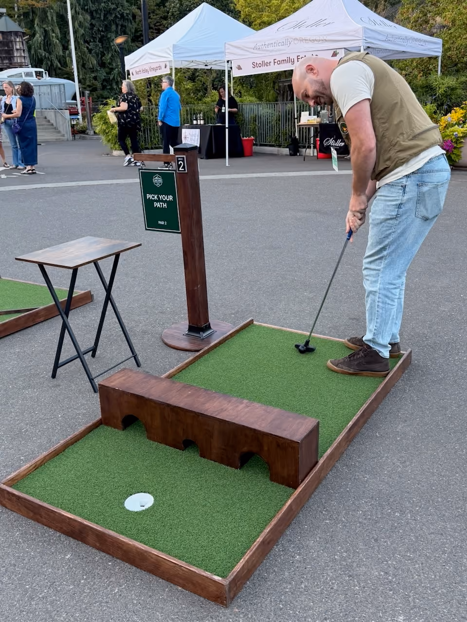 Guest putting over a bridge obstacle at an outdoor wine event